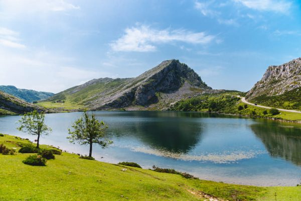 Lago asturiano con sierras de fondo y vegetación.