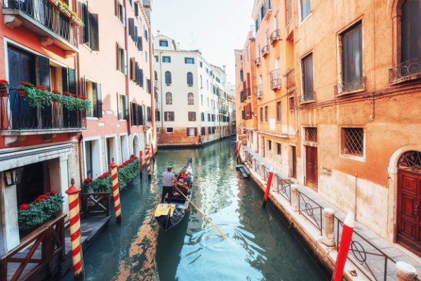 Góndola con personas navegando en canal de Venecia.