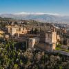 Imagen de aérea de la fortaleza de la Alhambra en Granada con las montañas nevadas detrás.