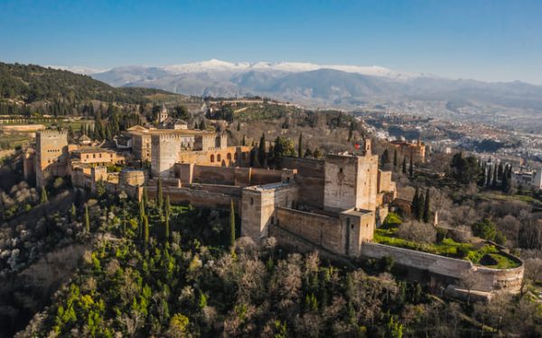 Imagen de aérea de la fortaleza de la Alhambra en Granada con las montañas nevadas detrás.