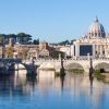 Imagen de la ciudad del Vaticano a lo lejos. Puente y rio en día soleado.